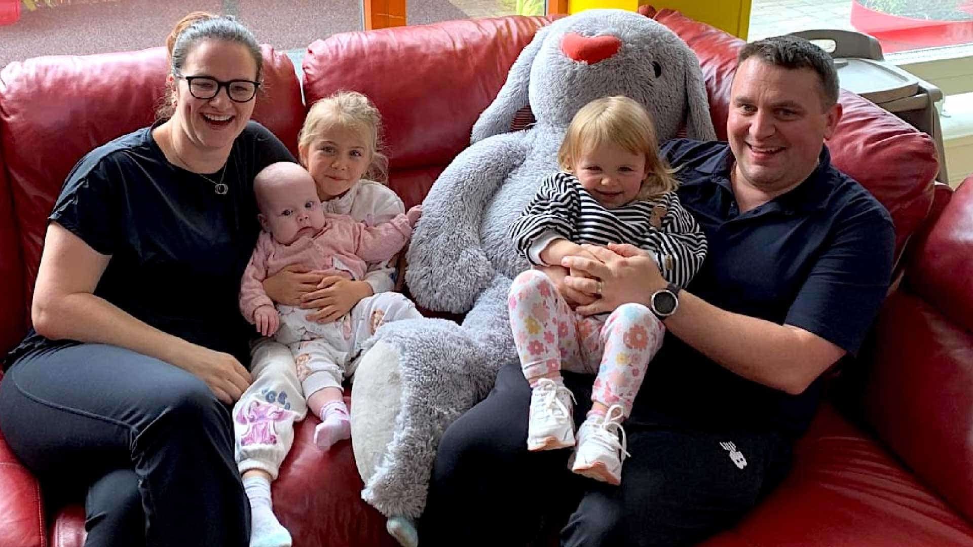 Family sitting on a couch with a large teddy bunny