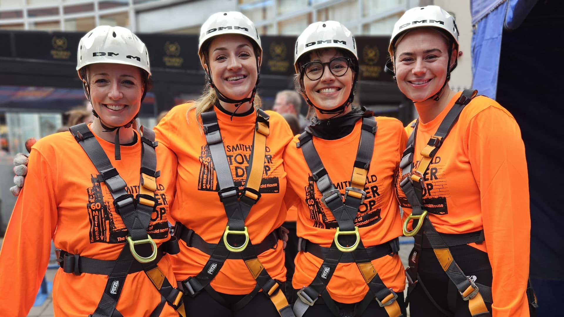 RMHC abseil event group girls in safety gear smiling at camera